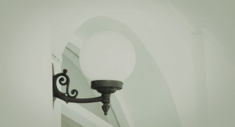Lampe d'exterieur noire avec un globe en verre installee sur un mur de batiment