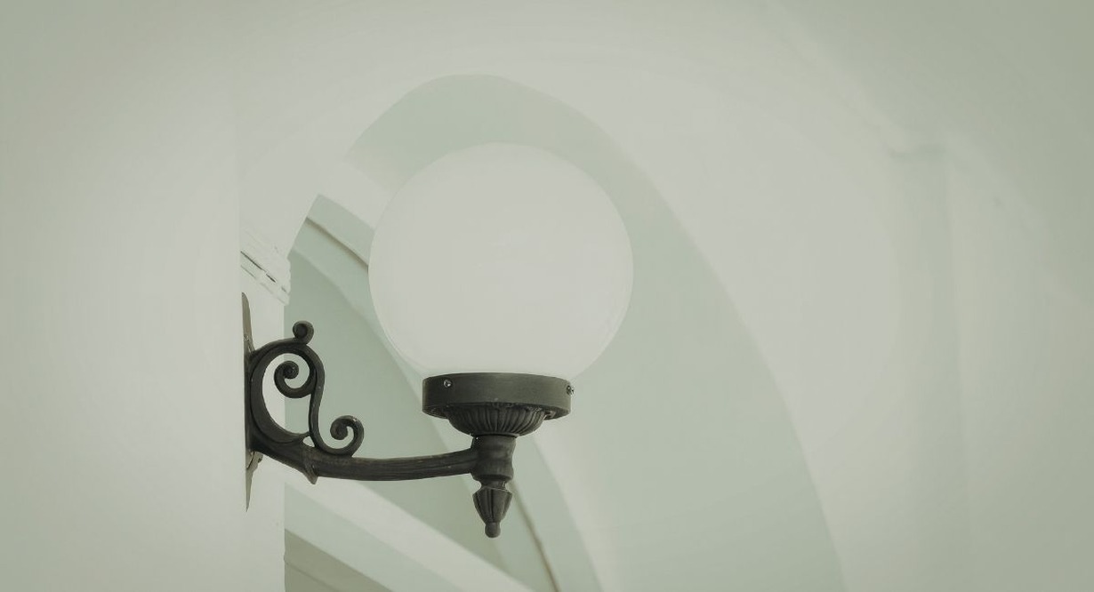 Lampe d'exterieur noire avec un globe en verre installee sur un mur de batiment