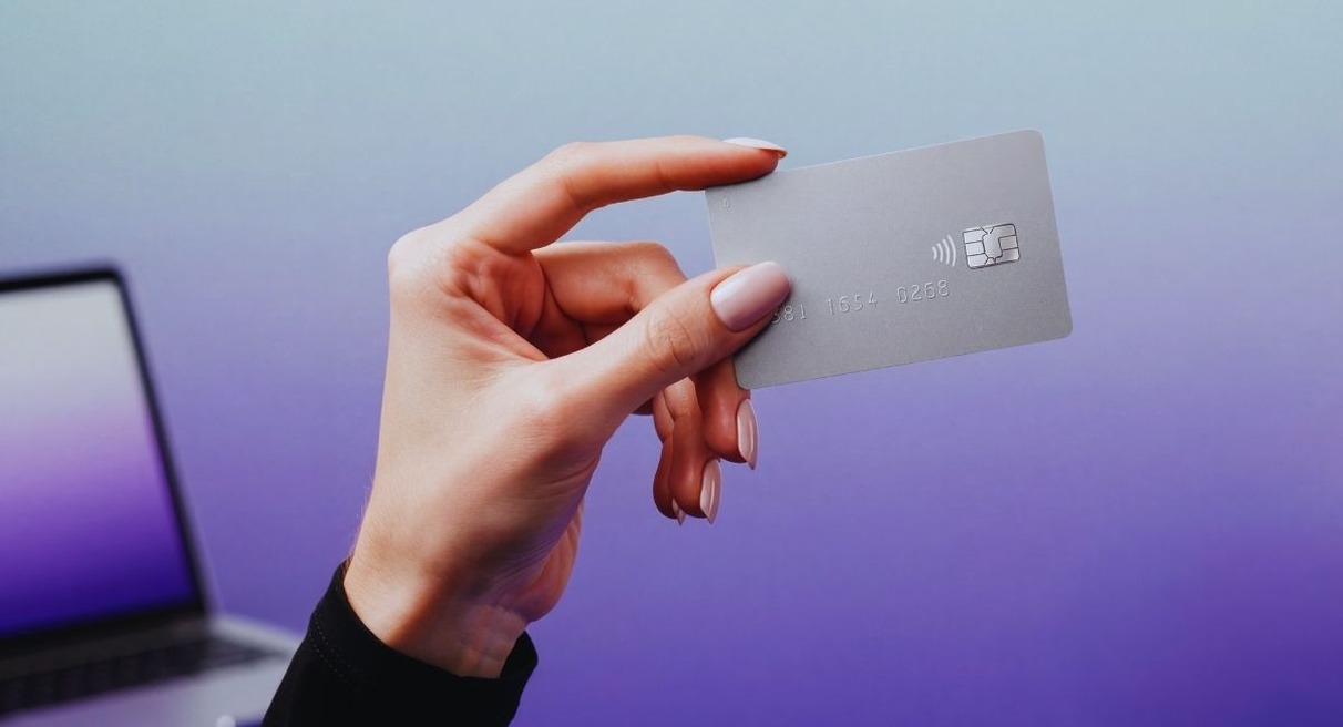 Personne tenant une carte bancaire devant l'ecran d'un ordinateur portable