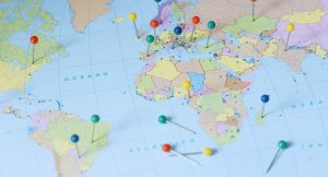 Carte du monde piquee de punaises de couleurs marquant differents pays