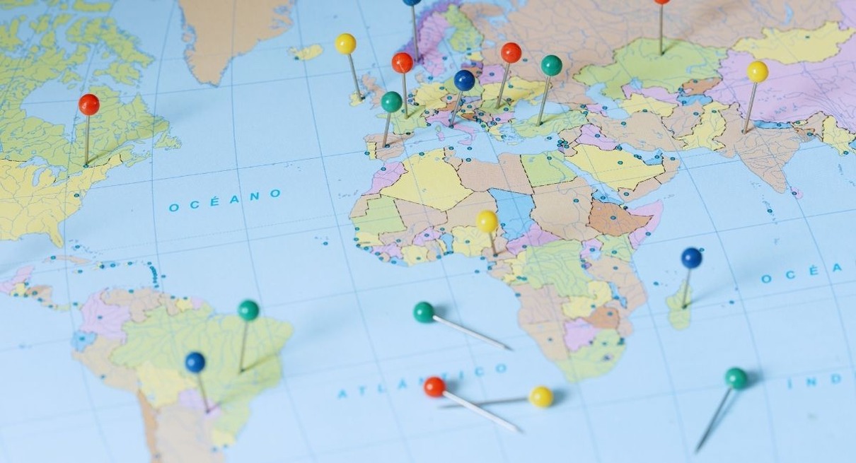 Carte du monde piquee de punaises de couleurs marquant differents pays