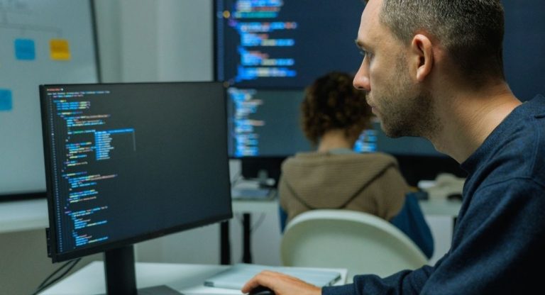 Developpeur informatique ecrivant des lignes de code sur l'ecran de son ordinateur