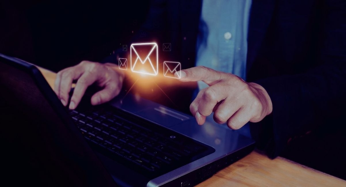 Professionnel sur ordinateur portable avec des icones d'enveloppes d'emails autour de l'ecran