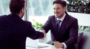 Deux hommes d'affaires souriants se serrant la main apres avoir conclu un accord