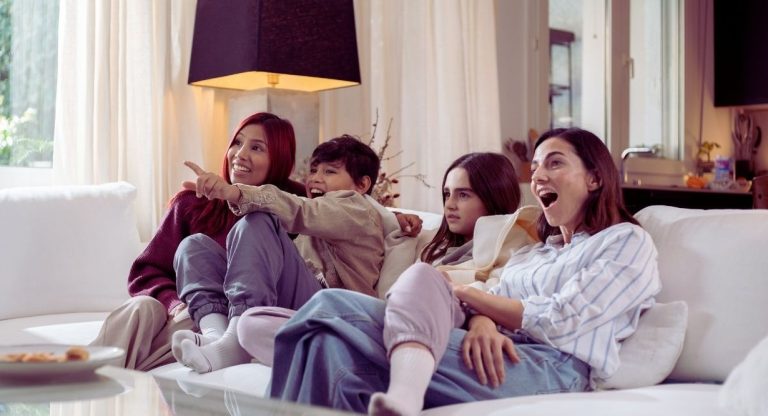 Famille reunie sur le canape dans un salon en train de regarder la television