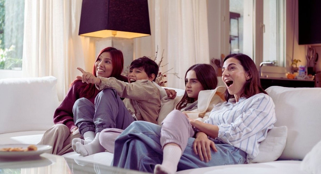 Famille reunie sur le canape dans un salon en train de regarder la television