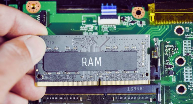 Main tenant une barrette de memoire vive RAM au dessus d une carte mere